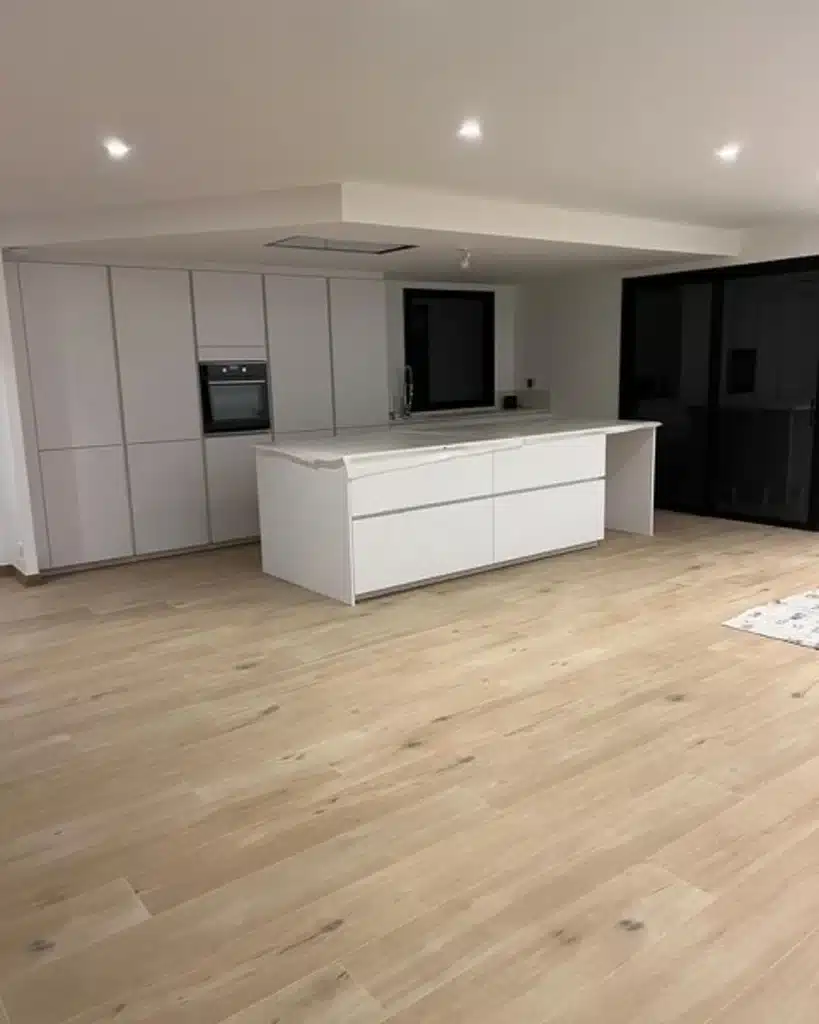 Cuisine contemporaine avec îlot central et sol effet bois clair