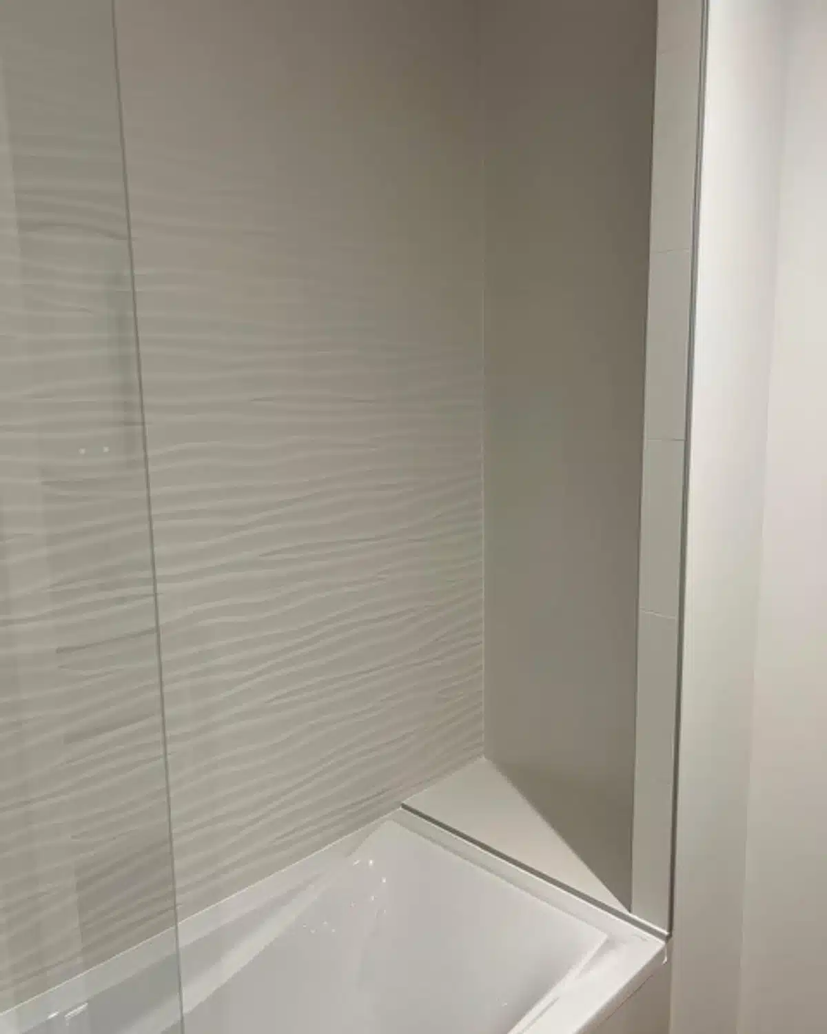 Mur de douche avec carrelage blanc à relief ondulé et receveur rectangulaire