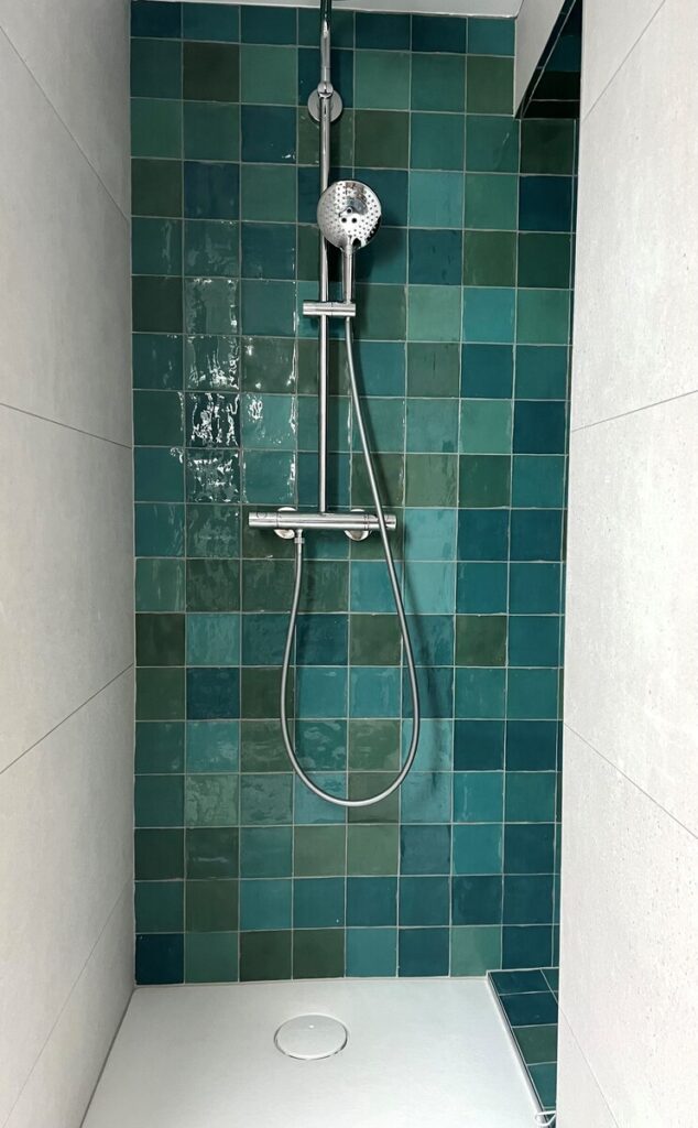Douche avec zelliges bleu canard et vert, robinetterie chromée et receveur blanc dans une salle de bain moderne.